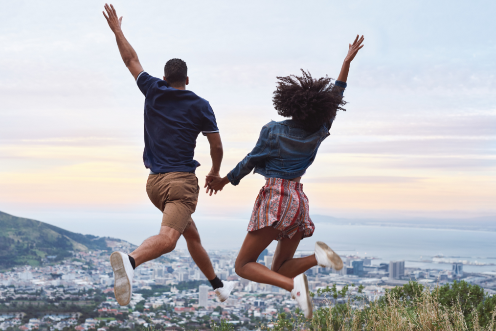 Two study abroad students jumping in the air holding hands